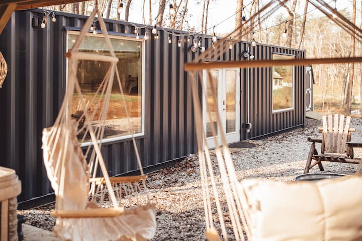 Steel Nest shipping container vacation rental in Rockbridge, Ohio, with hammock chairs and string lights