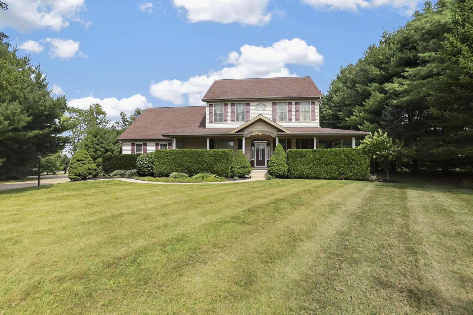 Exterior of 3588 Havensport Road NW, Carroll, Ohio, a two-story home with a wraparound porch and landscaped lawn
